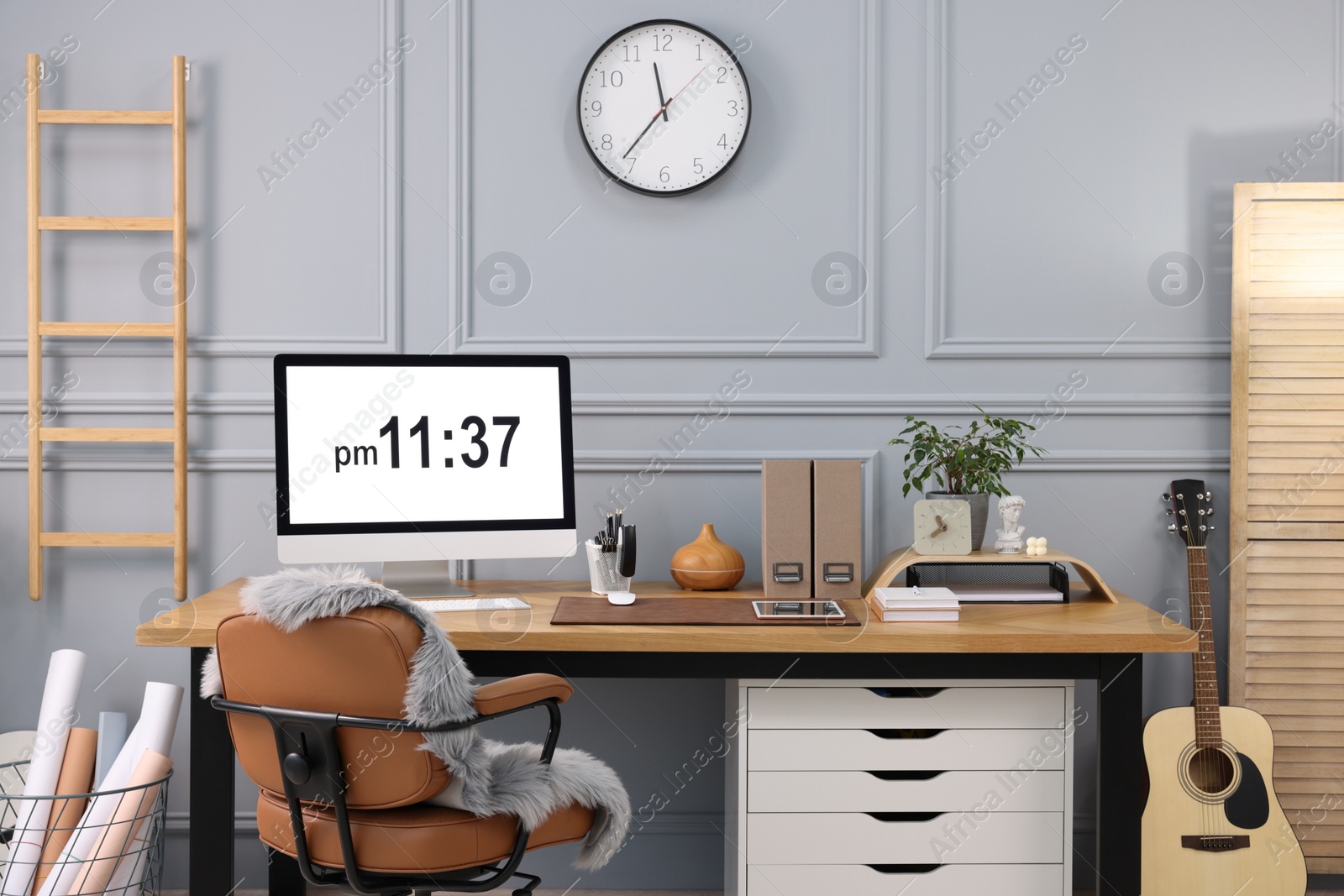 Photo of Stylish workplace with computer, houseplant and stationery on wooden desk near grey wall at home