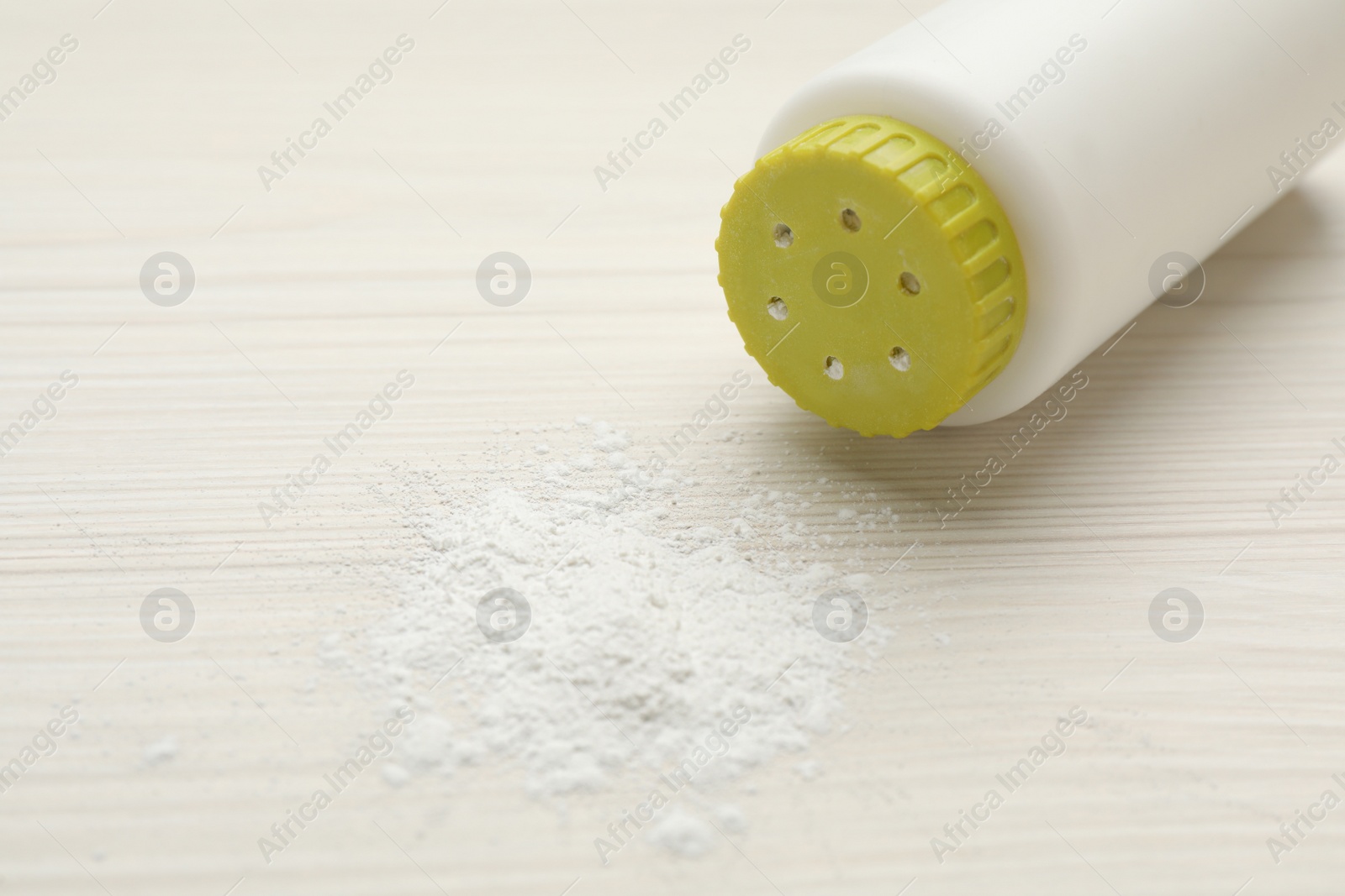 Photo of Bottle and scattered dusting powder on white wooden background. Baby cosmetic product