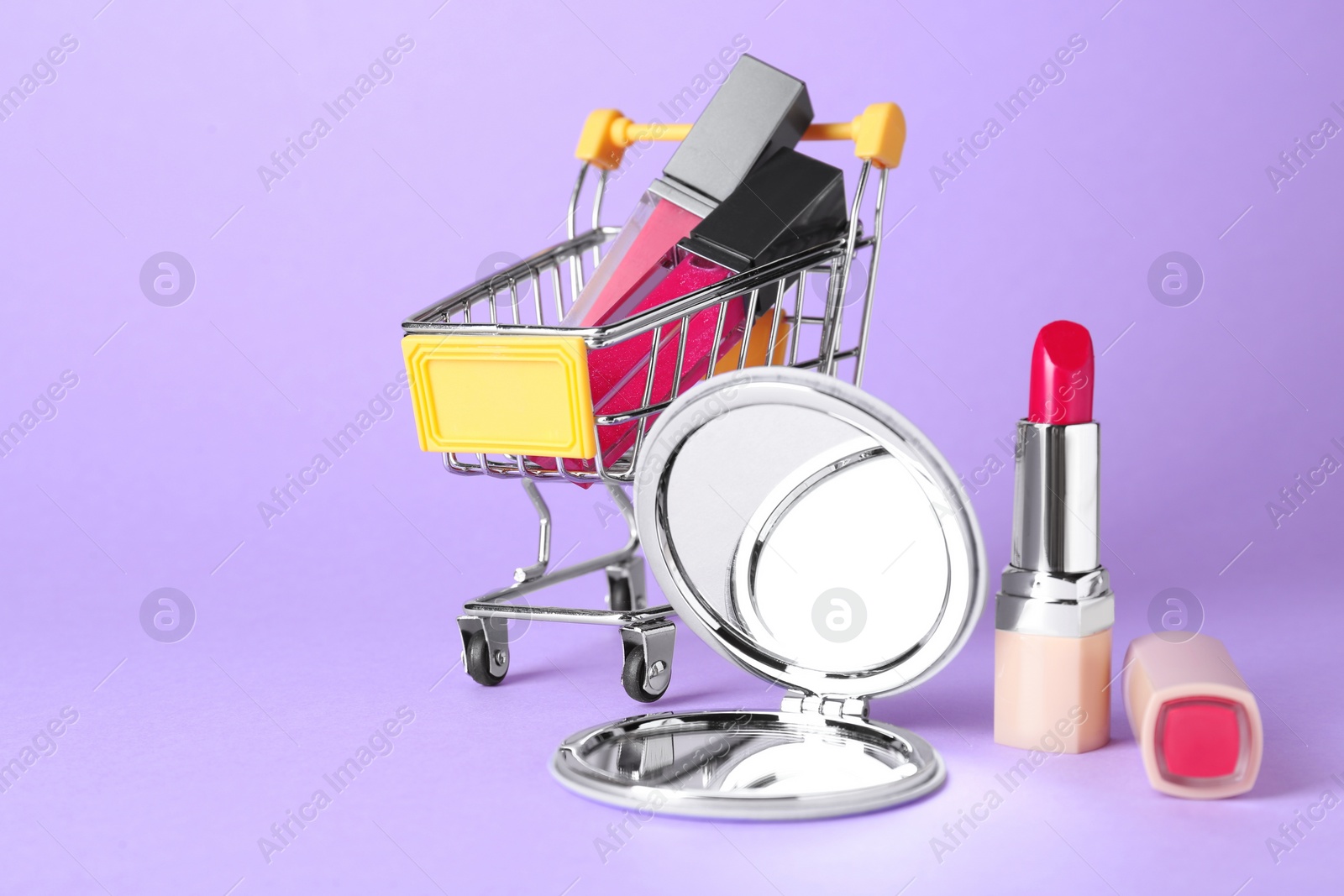 Photo of Stylish pocket mirror and makeup products on lilac background