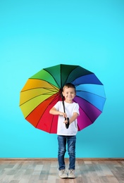 Photo of Little boy with rainbow umbrella near color wall