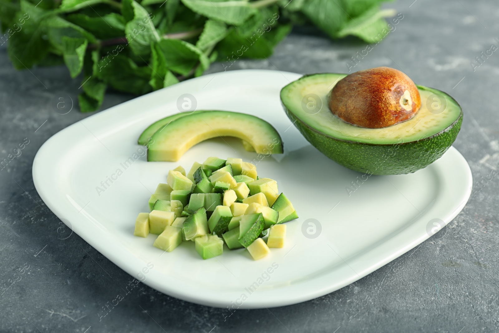 Photo of Plate with cut avocado on grey background