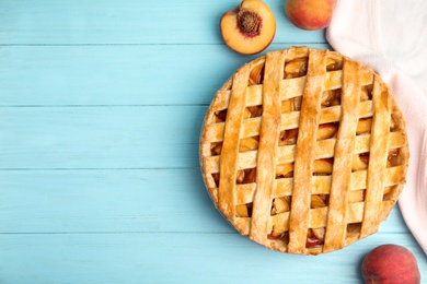 Delicious fresh peach pie on light blue wooden table, flat lay. Space for text