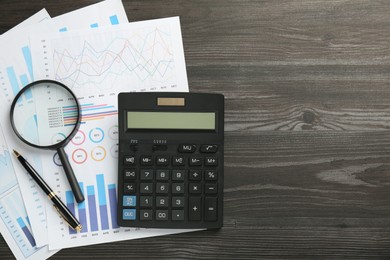 Accounting documents, magnifying glass, calculator and pen on wooden table, top view. Space for text