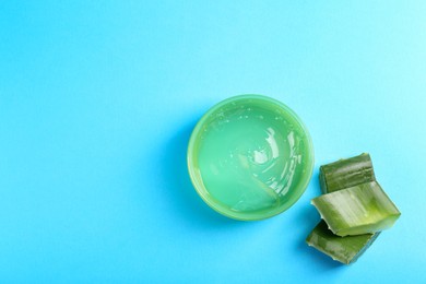 Aloe gel and plant on light blue background, flat lay. Space for text