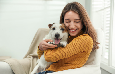 Photo of Young woman with her cute Jack Russell Terrier at home. Lovely pet