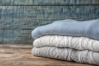 Photo of Stack of folded knitted sweaters on table. Space for text