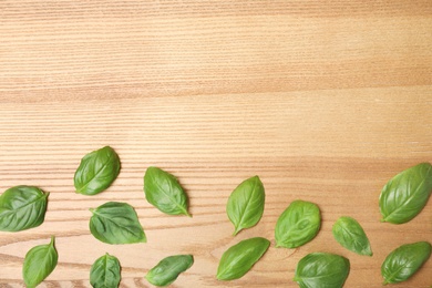 Photo of Fresh green basil leaves and space for text on wooden background, top view