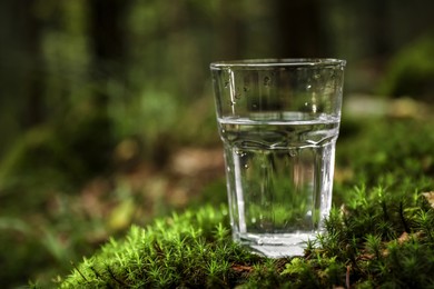 Photo of Glass of water on green grass outdoors. Space for text