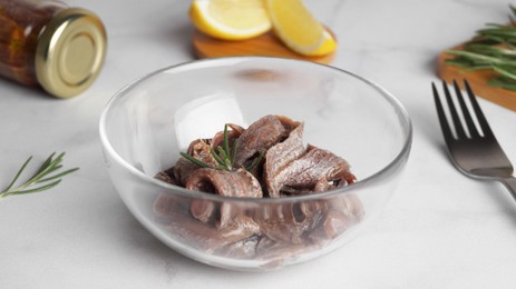 Photo of Canned anchovy fillets in glass bowl on white marble table