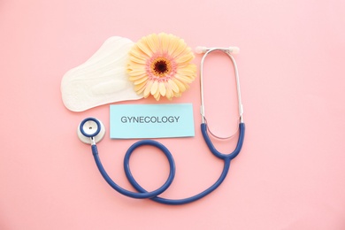 Photo of Flat lay composition with stethoscope, flower and menstrual pads on color background. Gynecological care