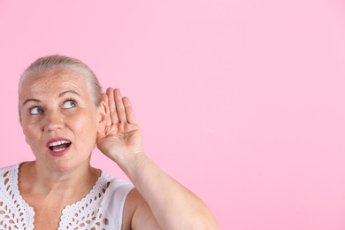 Photo of Mature woman with hearing problem on color background. Space for text