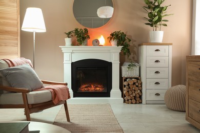 Stylish fireplace near comfortable armchair in cosy living room. Interior design