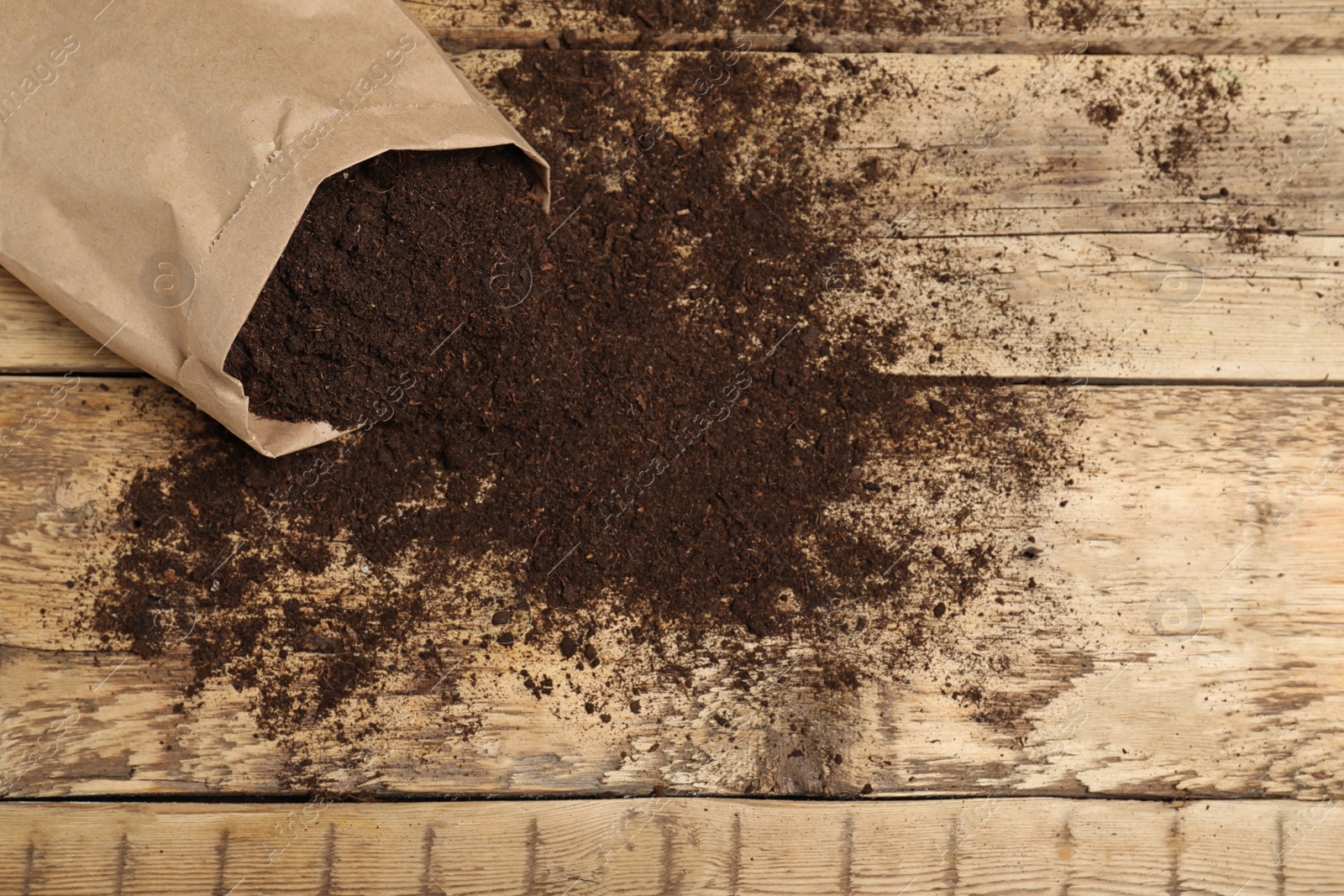 Photo of Paper bag and soil on wooden table, top view with space for text. Gardening season