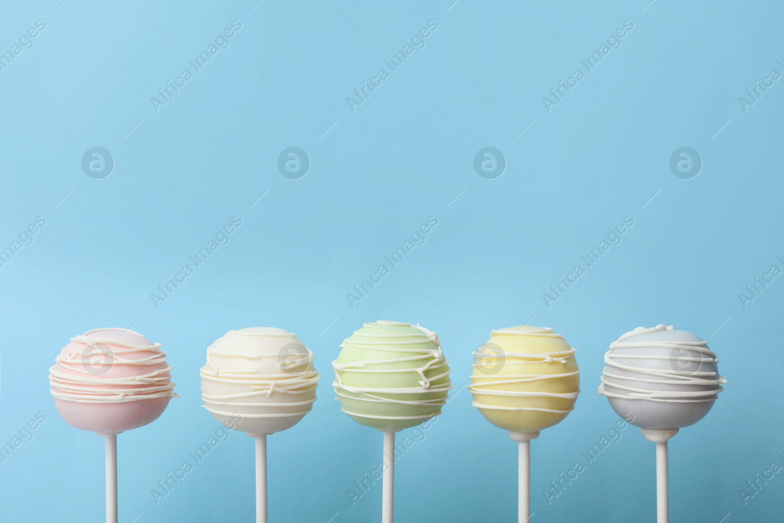 Photo of Sweet cake pops on light blue background, space for text