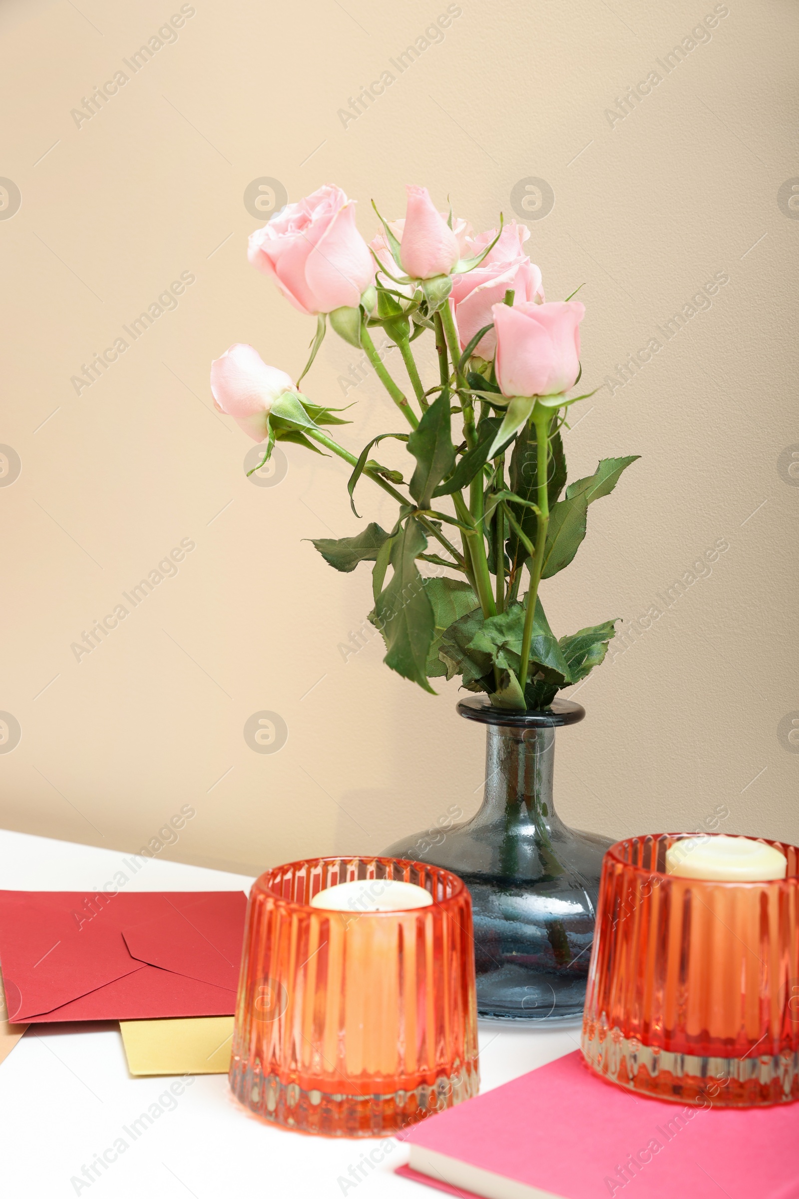 Photo of Greeting card, flowers and candles on white table indoors