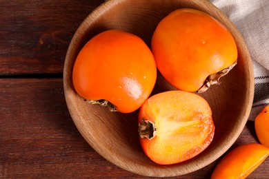 Delicious ripe persimmons on wooden table, top view