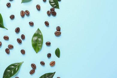 Photo of Fresh green coffee leaves and beans on light blue background, flat lay. Space for text