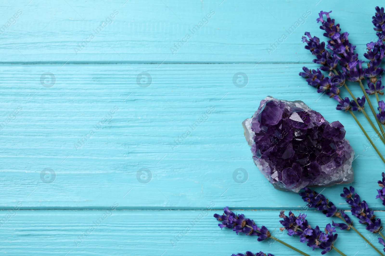 Photo of Amethyst, lavender and space for text healing herbs on light blue wooden table, flat lay.