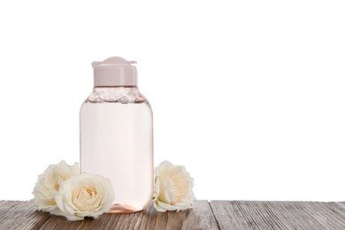 Photo of Micellar water and roses on wooden table against white background. Space for text