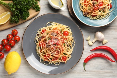 Delicious pasta with anchovies, tomatoes and parmesan cheese served on white wooden table, flat lay