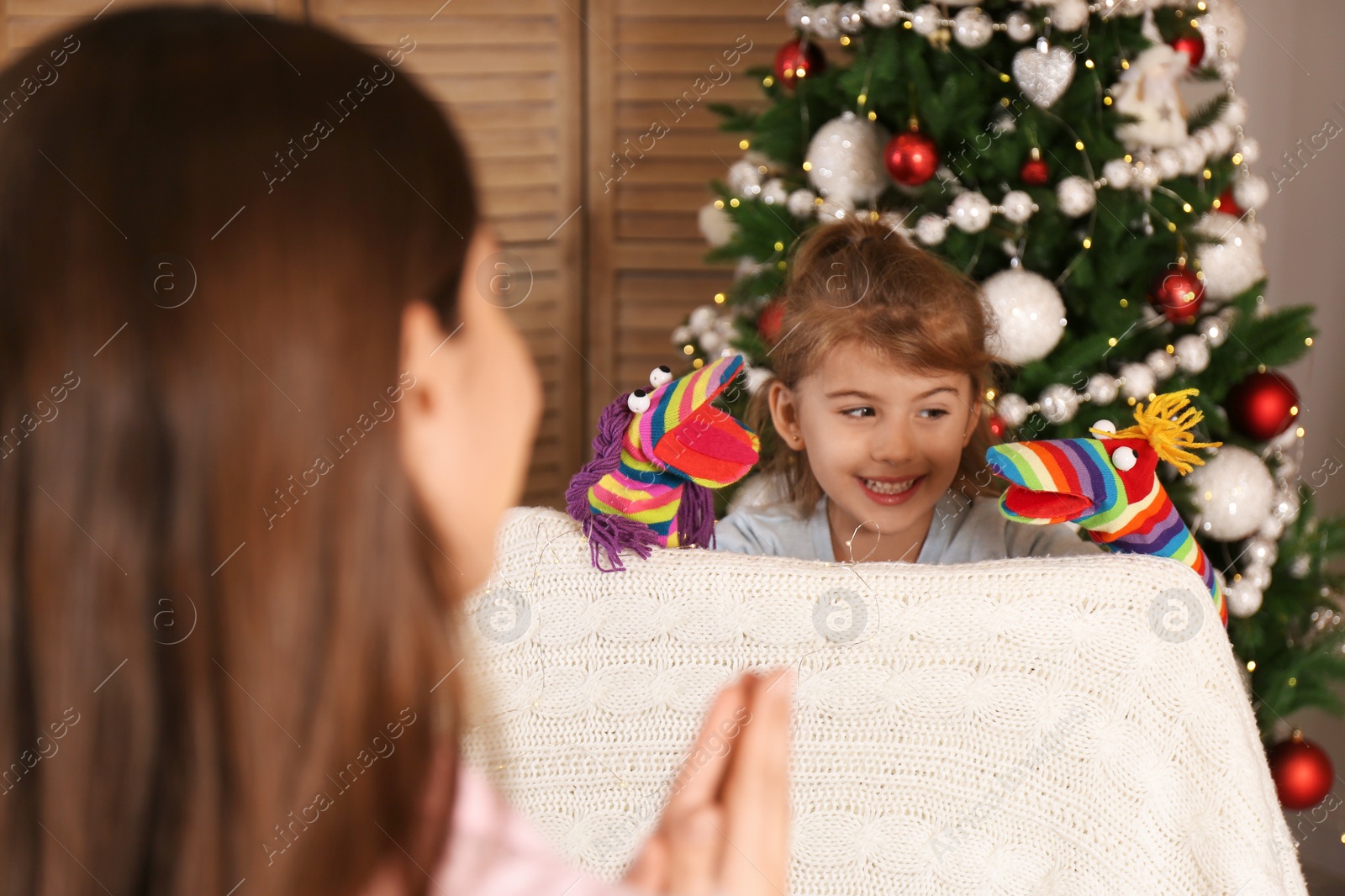 Photo of Cute little girl performing puppet show for her mother at home