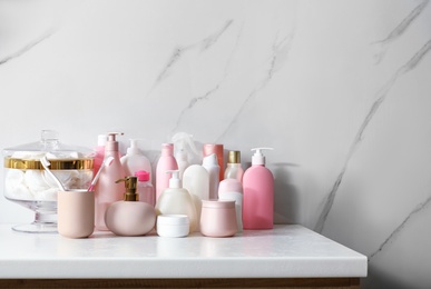 Stick deodorant and different toiletry on marble table near light wall, space for text