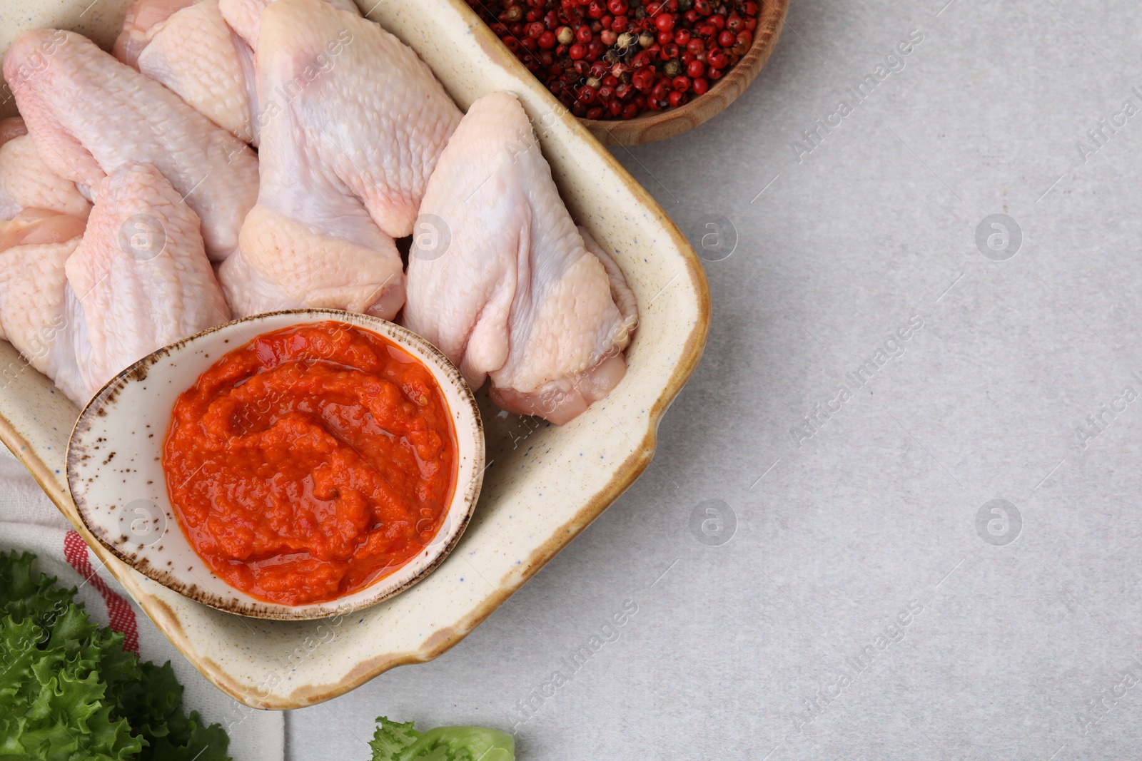 Photo of Flat lay composition with marinade, raw chicken and other products on light textured table. Space for text