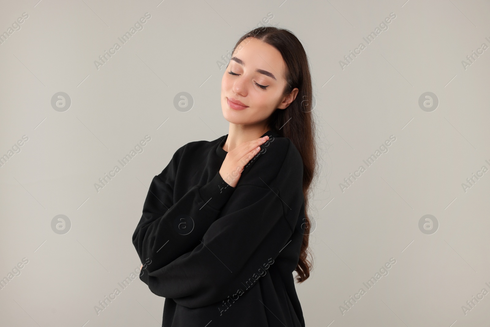 Photo of Beautiful young woman in stylish warm sweater on grey background