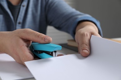 Photo of Man with papers using stapler at table, closeup