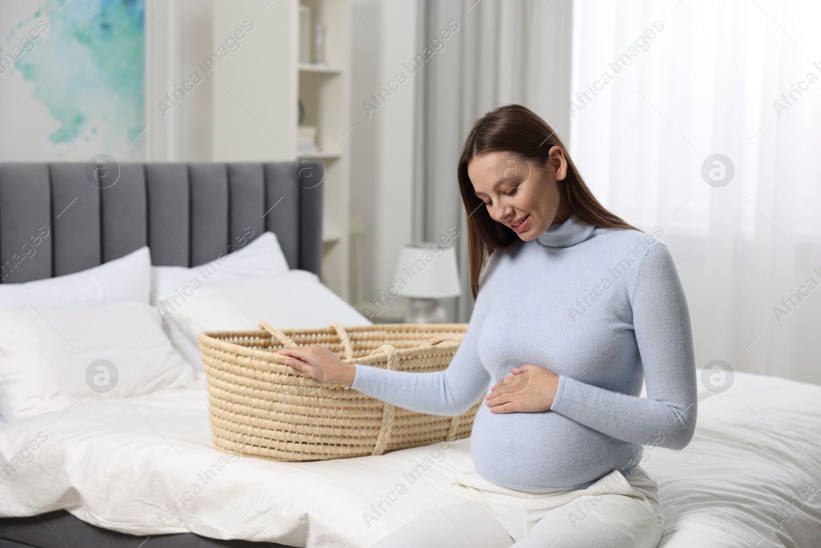 Photo of Beautiful pregnant woman with baby basket in bedroom