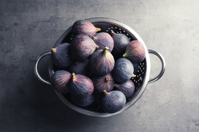 Photo of Colander with fresh ripe figs on gray background, top view