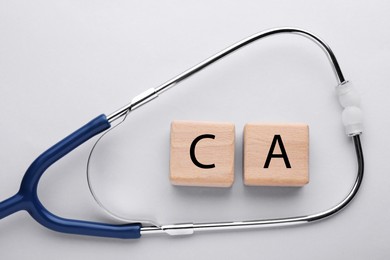 Photo of Stethoscope and calcium symbol madewooden cubes with letters on light grey background, flat lay