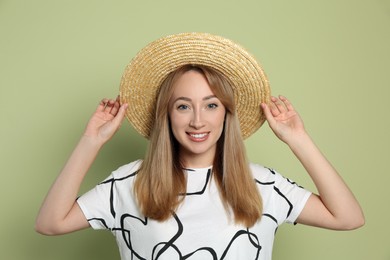 Photo of Beautiful young woman wearing straw hat on light green background. Stylish headdress