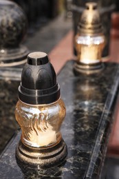 Photo of Grave lantern with candle on granite surface at cemetery