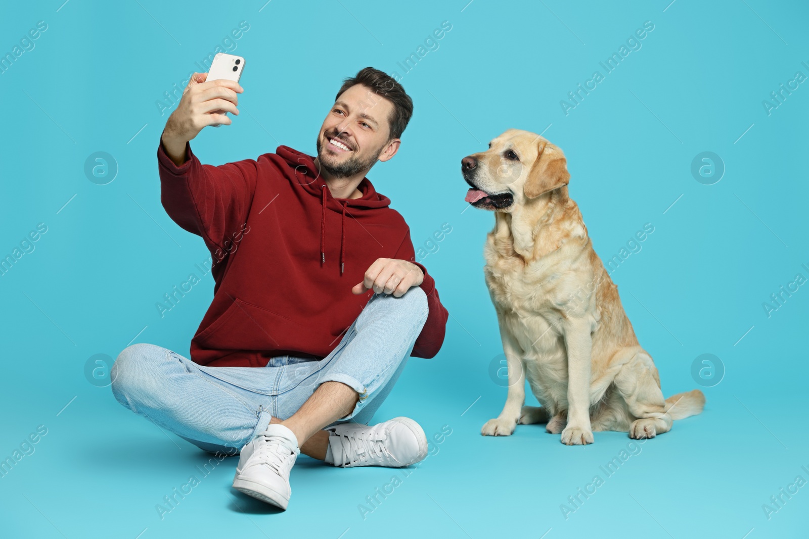 Photo of Man taking selfie with his cute Labrador Retriever on turquoise background