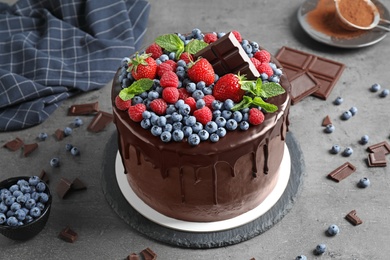 Photo of Freshly made tasty chocolate cake decorated with berries on grey table