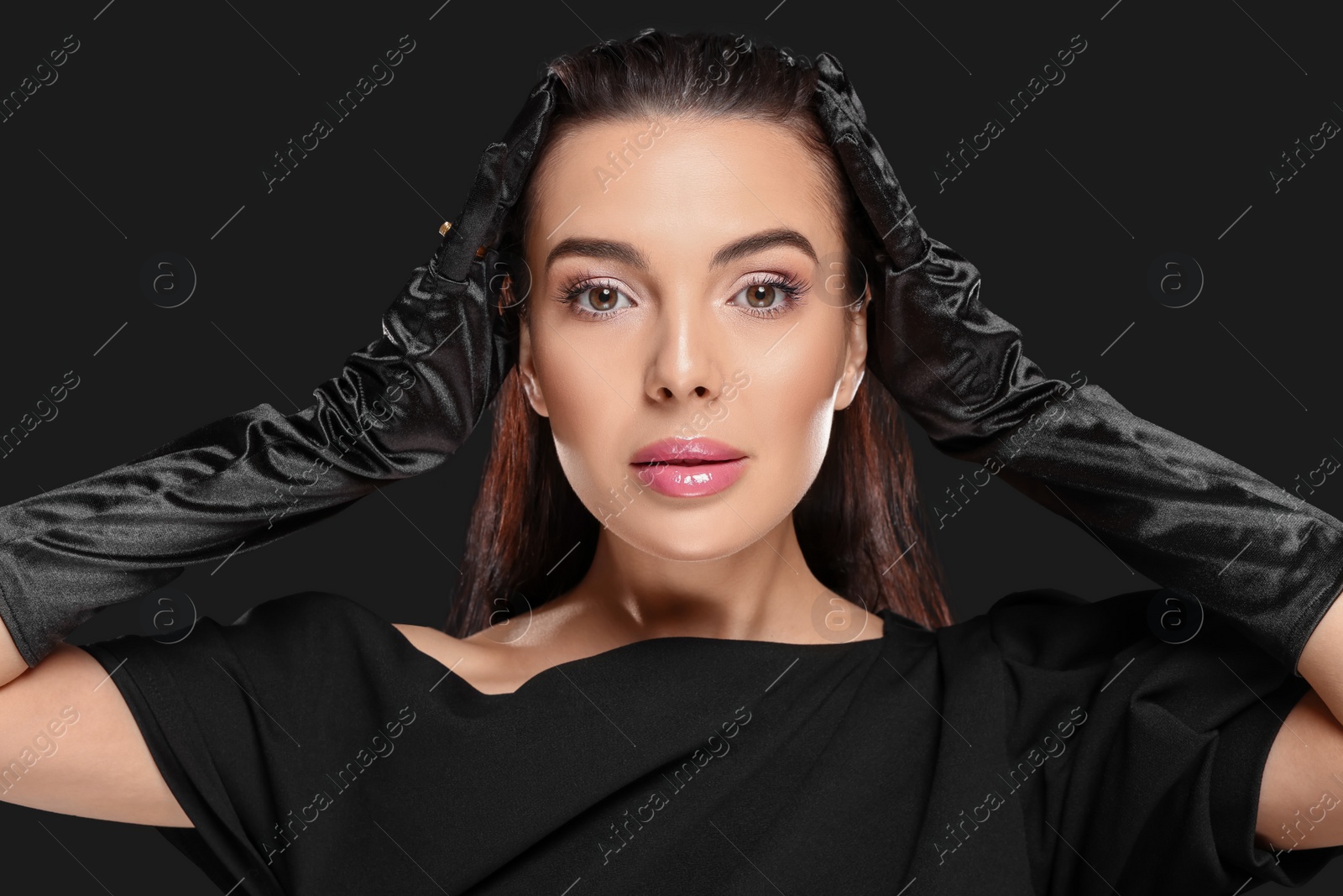 Photo of Portrait of beautiful young woman in elegant evening gloves on black background