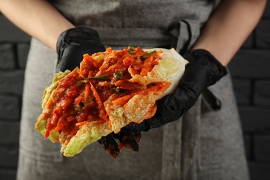 Woman preparing spicy cabbage kimchi indoors, closeup