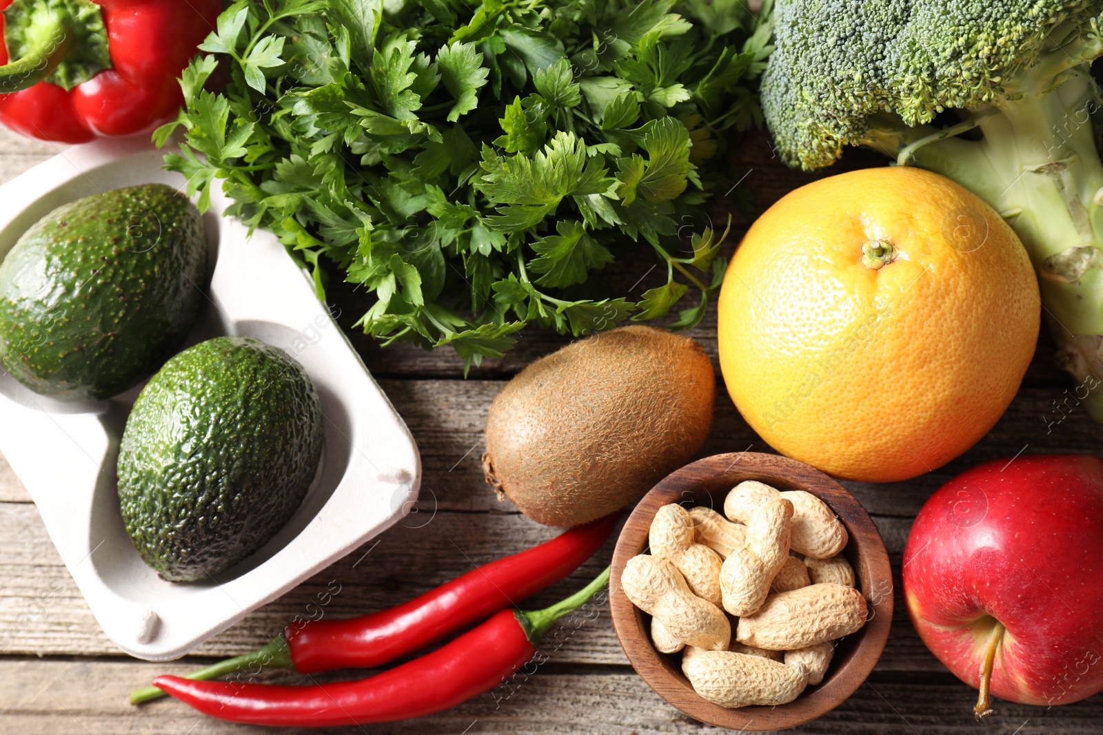 Photo of Healthy meal. Different vegetables and peanuts on wooden table, flat lay