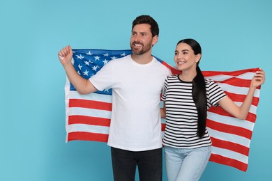 4th of July - Independence Day of USA. Happy couple with American flag on light blue background. Space for text