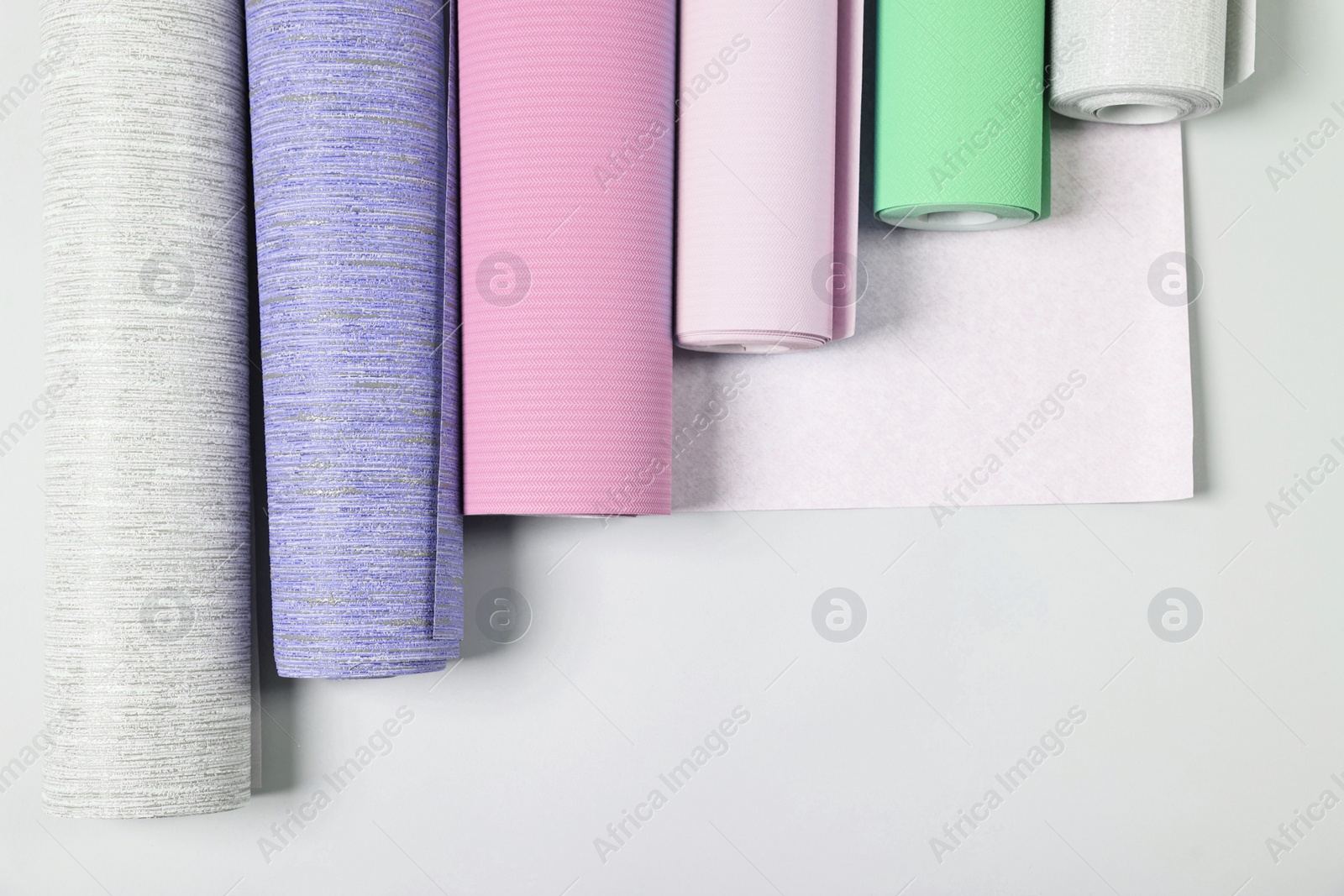 Image of Different wallpaper rolls on light grey background, flat lay