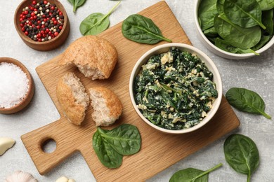 Photo of Tasty spinach dip with egg, bread and spices on grey table, flat lay