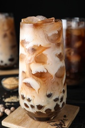 Photo of Tasty brown milk bubble tea on black wooden table, closeup