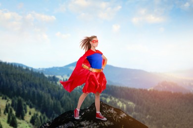 Superhero, motivation and power. Woman in cape and mask on high top in mountains