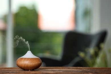 Aroma oil diffuser lamp on table against blurred background