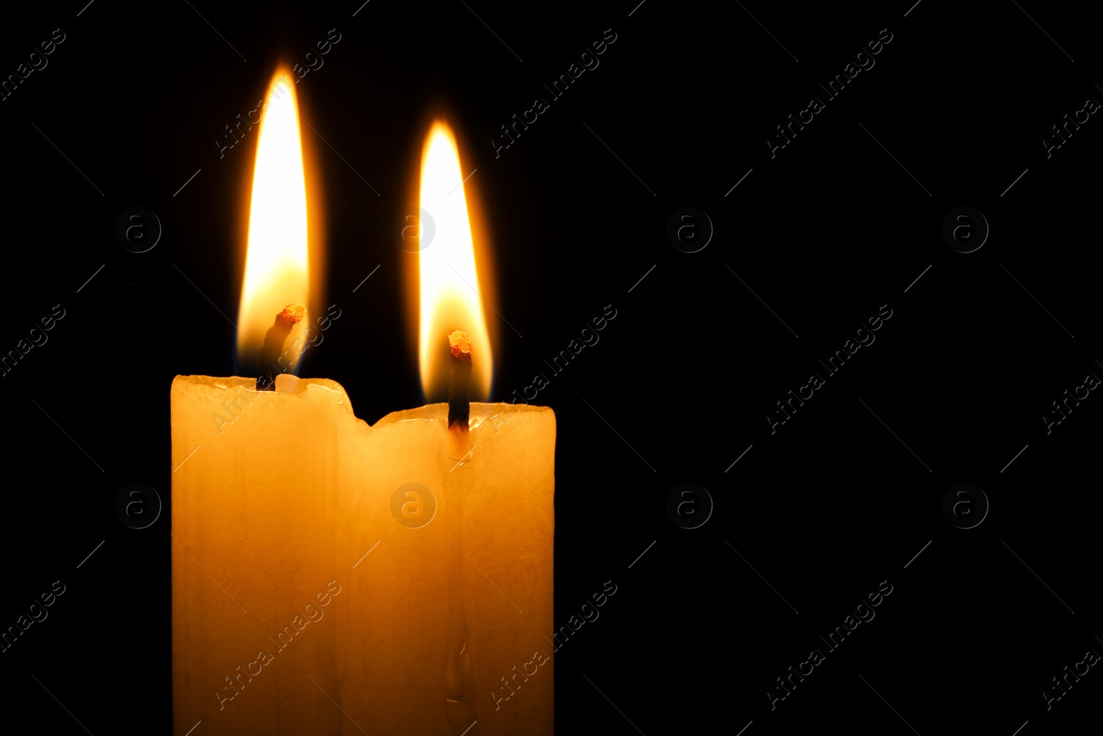 Photo of Burning candles on black background, closeup. Space for text