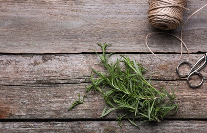 Photo of Fresh green rosemary, twine and scissors on wooden table, flat lay. Space for text