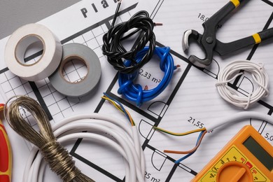 Different wires, tools and electrical schemes on grey table, closeup