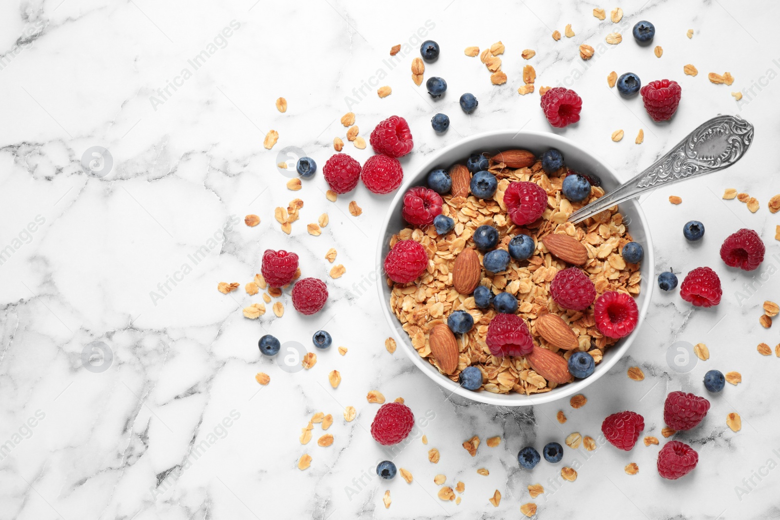 Photo of Healthy homemade granola with berries and almonds on white marble table, top view. Space for text