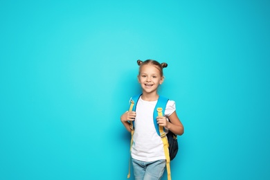 Little school child with backpack on color background